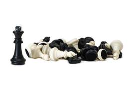 one chess piece standing next to a pile of overturned pieces